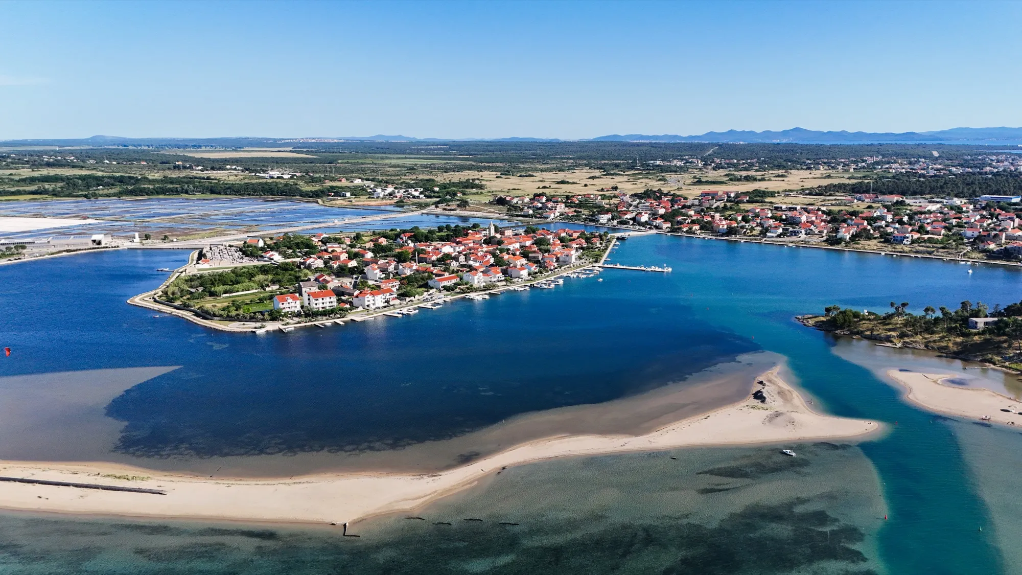Pogled iz zraka na ninsku starogradsku jezgru na otočiću s pješčanim sprudom i tirkiznom lagunom